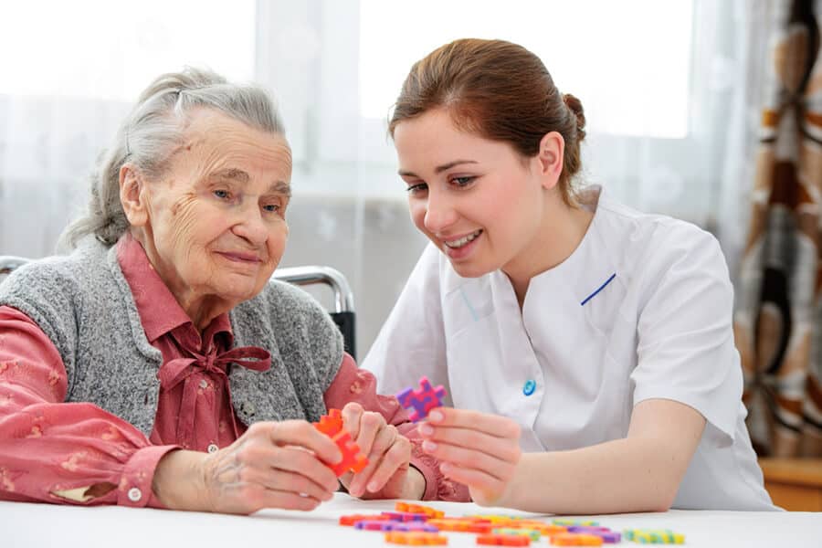 Nurse playing jigsaw puzzle with a woman in a nursing home